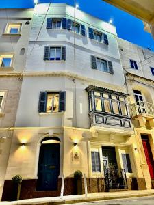 a white building with windows and a blue door at Nautilus Boutique Townhouse in Sliema