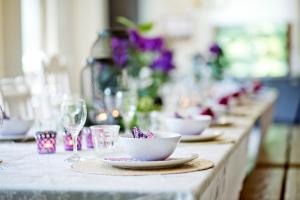 una mesa larga con platos y vasos y flores púrpuras en Westerwald Ferien Villa - 21 Personen - Kino, Bar, Sauna und Whirlpool en Schutzbach