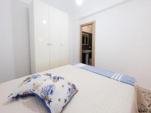 ein weißes Bett mit einem blauen und weißen Kissen darauf in der Unterkunft Isola Serena in Favignana