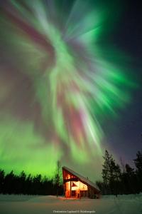 un edificio con la aurora boreal en el cielo en Nivunki Village, en Muonio