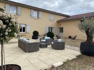 a patio with couches and chairs in front of a house at Domaine de la Noiseraie in Belleville-sur-Saône