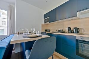 Una cocina con gabinetes azules y una mesa y sillas. en Welcome to Lucie House, en Marly-le-Roi 3 fotos más