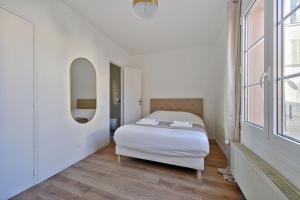 Un dormitorio blanco con una cama y un espejo. en Welcome to Lucie House, en Marly-le-Roi
