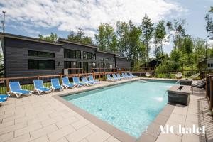 a swimming pool with lounge chairs and a house at Achille - Wooded with spa and sauna in Pont-Rouge