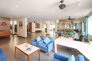 a woman sitting in a lobby with blue chairs at ÊMM Hotel Hoi An in Hoi An