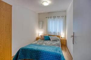 1 dormitorio con 1 cama con edredón azul y ventana en Apartments Suki, en Rovinj