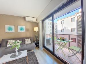 een woonkamer met een bank en een groot raam bij Nestor&Jeeves - RIVOLI PALM - City center - Very close sea in Nice