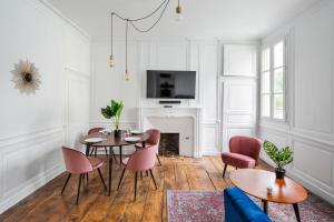 een woonkamer met een tafel en stoelen en een open haard bij Appartements Le 31bis in Rennes