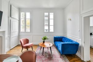 uma sala de estar com um sofá azul e duas cadeiras em Cervantes - Le 31bis em Rennes