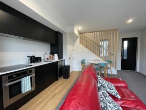 a living room with a red couch in a kitchen at Stadium View Suite in Christchurch