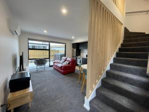 a living room with a staircase and a red couch at Stadium View Suite in Christchurch