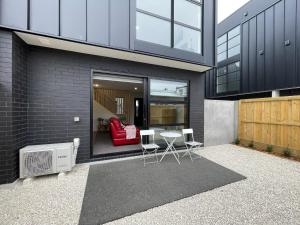 a house with a patio with a table and chairs at Stadium View Suite in Christchurch