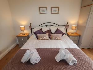 a bedroom with a bed with white slippers on it at Beau Cottage in Bewdley