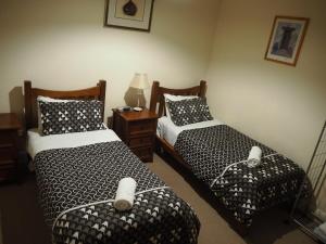 a bedroom with two beds and a table with a lamp at Odeon Cottage - Part of Harrietts in Unley