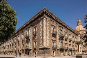 un gran edificio de ladrillo con una cúpula encima en Benedettini - Suites, en Catania