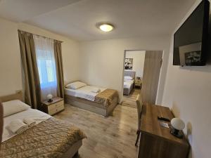 um quarto com 2 camas, uma secretária e um espelho. em B&B Villa Ellena em Medjugorje
