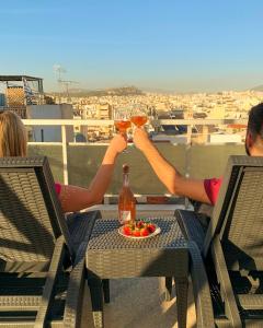 Dos personas están bebiendo cócteles en un balcón en Penthouse with urban and partial sea view! en Atenas