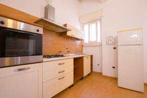 eine Küche mit weißen Schränken, einer Spüle und einem Kühlschrank in der Unterkunft Casa Puccini Altstadt 5 Minuten | 8 km Meer in San Vito dei Normanni
