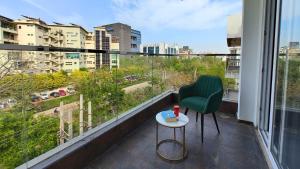 Un balcón con una silla verde y una mesa. en AVA Hotels and Corporates Millennium City en Gurgaon