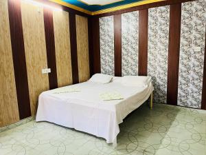 1 dormitorio con 1 cama blanca y paredes de madera en Maharastra Bhavan Atithi Grah en Naimishāranya