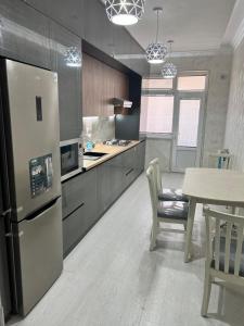 uma cozinha com um frigorífico de aço inoxidável e uma mesa em Mega house em Bukhara