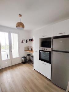 una cocina con armarios blancos y un aparato de acero inoxidable en Le Cosy Valcros, design et confort, en Aix-en-Provence