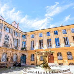 un grand bâtiment avec une fontaine devant lui dans l'établissement Le Cosy Valcros, design et confort, à Aix-en-Provence