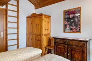 a bedroom with a bed and a wooden cabinet at Samont Appartment 5 in Arabba