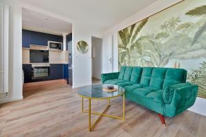 Una sala de estar con un sofá verde y una mesa. en Welcome to the green House, en Marly-le-Roi