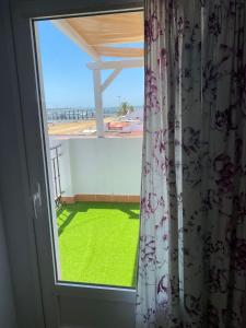 a window with a view of a green yard at Apartamentos Centro El Rompido in El Rompido