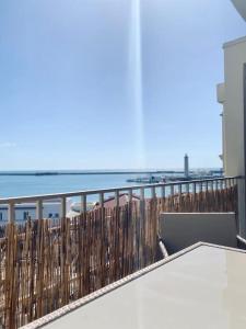 Un balcón con una mesa y una computadora portátil encima. en Panoramic - Magnifique T3, Climatisé avec Parking, en Sète