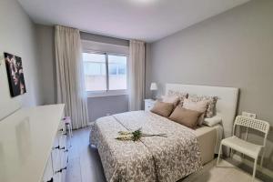 ein weißes Schlafzimmer mit einem Bett und einem Fenster in der Unterkunft VibesCoruña - Ángel 72 in A Coruña