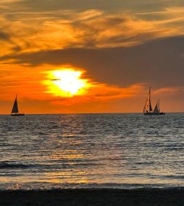 two sailboats in the ocean at sunset at Luxury home in quiet neighbourhood near beach in The Hague