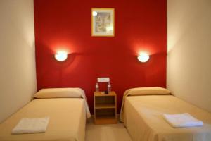 Habitación con 2 camas y pared roja. en Hotel Sant Jordi en Segur de Calafell