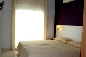 Hotel Sant Jordi في سيجور دي كالافيل: غرفة نوم بسرير ونافذة كبيرة