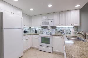 una cocina con armarios blancos y electrodomésticos blancos en Surfside II #109 home, en Coffeyville