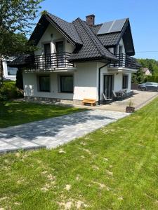 uma grande casa branca com um jardim de relva em frente em Dom w Zawadzie Lanckorońskiej 101 em Zakliczyn