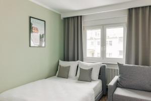 1 dormitorio con cama, sofá y ventana en Homaris Apartments Frankfurt en Frankfurt