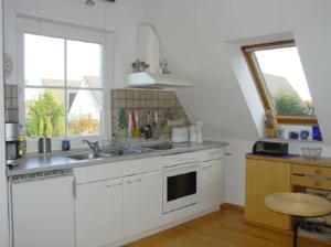 a kitchen with white cabinets and a sink and two windows at Ferienwohnung Frische Brise in Drewoldke