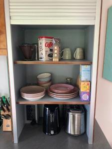 a shelf with plates and other items in a kitchen at Tiny House im Seecontainer mit Parkplatz, Glasfaser, Netflix, Veranda und gehobener Ausstattung in Coburg