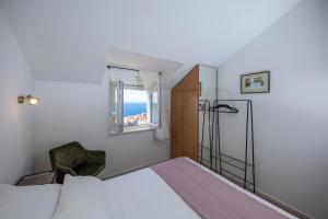 1 dormitorio con 1 cama con ventana y silla en Apartments Mariana, en Dubrovnik