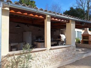 un patio avec un auvent sur un mur de briques dans l'établissement Maison de 2 chambres avec piscine partagee jardin clos et wifi a Avignon, à Avignon