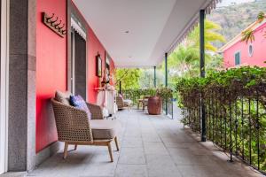 a patio with wicker chairs and a pink wall at Quinta da Tia Briosa by Madeira Sun Travel in Ponta do Sol