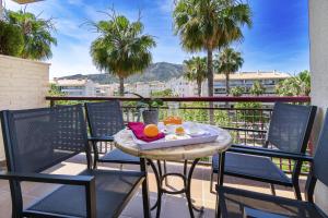 a table and chairs on a balcony with palm trees at Apartamentos Albir Confort - Avenida 1 dorm in Albir