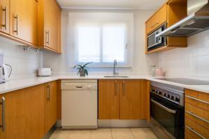 a kitchen with wooden cabinets and a sink and a dishwasher at Apartamentos Albir Confort - Avenida 1 dorm in Albir