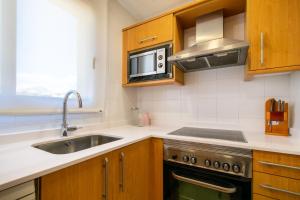 a kitchen with a sink and a microwave at Apartamentos Albir Confort - Avenida 1 dorm in Albir