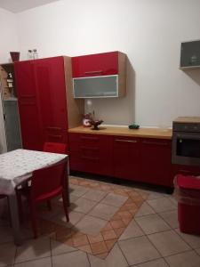 La cuisine est équipée de placards rouges, d'une table et d'un four micro-ondes. dans l'établissement Casa Butera, à Bagheria