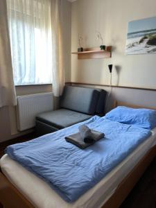 uma cama com um cobertor azul e um chapéu em Gyarmati Panzió & Étterem em Veszprém