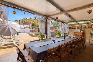 einem großen Tisch mit Stühlen und einem Sonnenschirm auf einer Terrasse in der Unterkunft Cal Ramon con piscina in Rubí