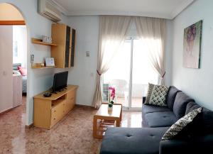 uma sala de estar com um sofá azul e uma televisão em Sol, mar y arena em Torrevieja